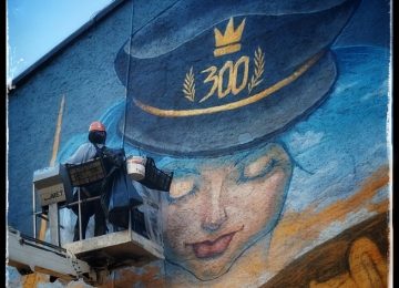 A picture showing the artist Chus at work on "the marching band” mural