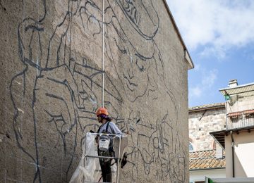 A picture showing the artist Chus at work on "the marching band” mural