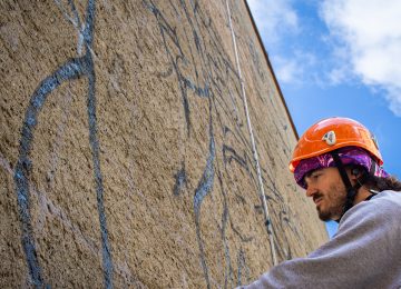 A picture showing the artist Chus at work on "the marching band” mural