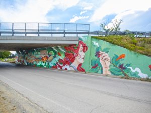 Photo of Chus’s mural under a highway overpass in Italy, depicting the allegory of wild Nature