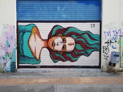 Mural portraying a woman with a fish on her forhead Street Art by Chus in Athens
